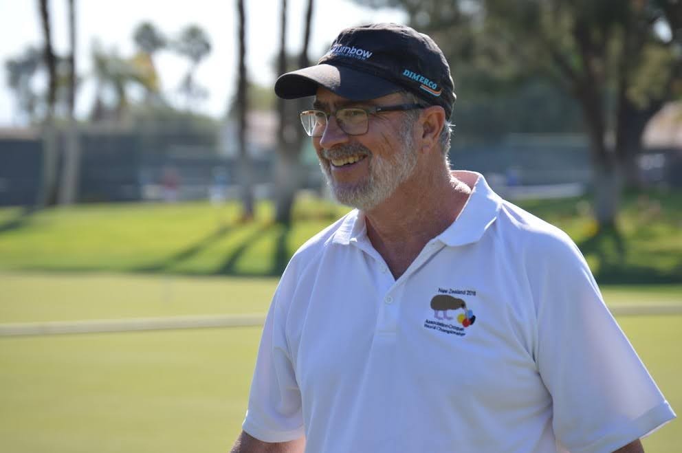 A smiling player in whites and a cap on the lawn