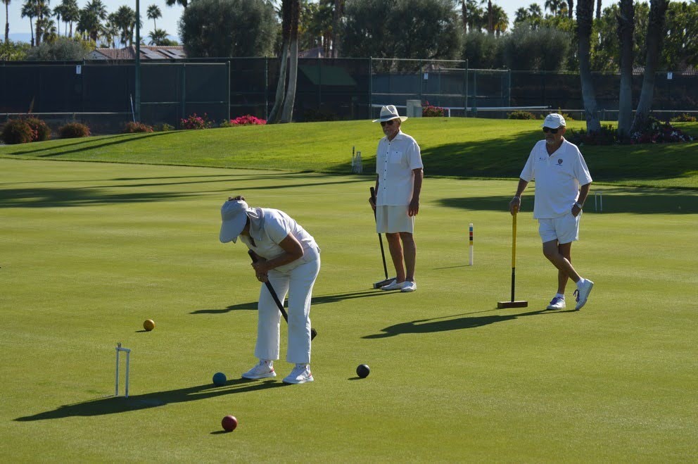 A member lining up a shot while two players look on